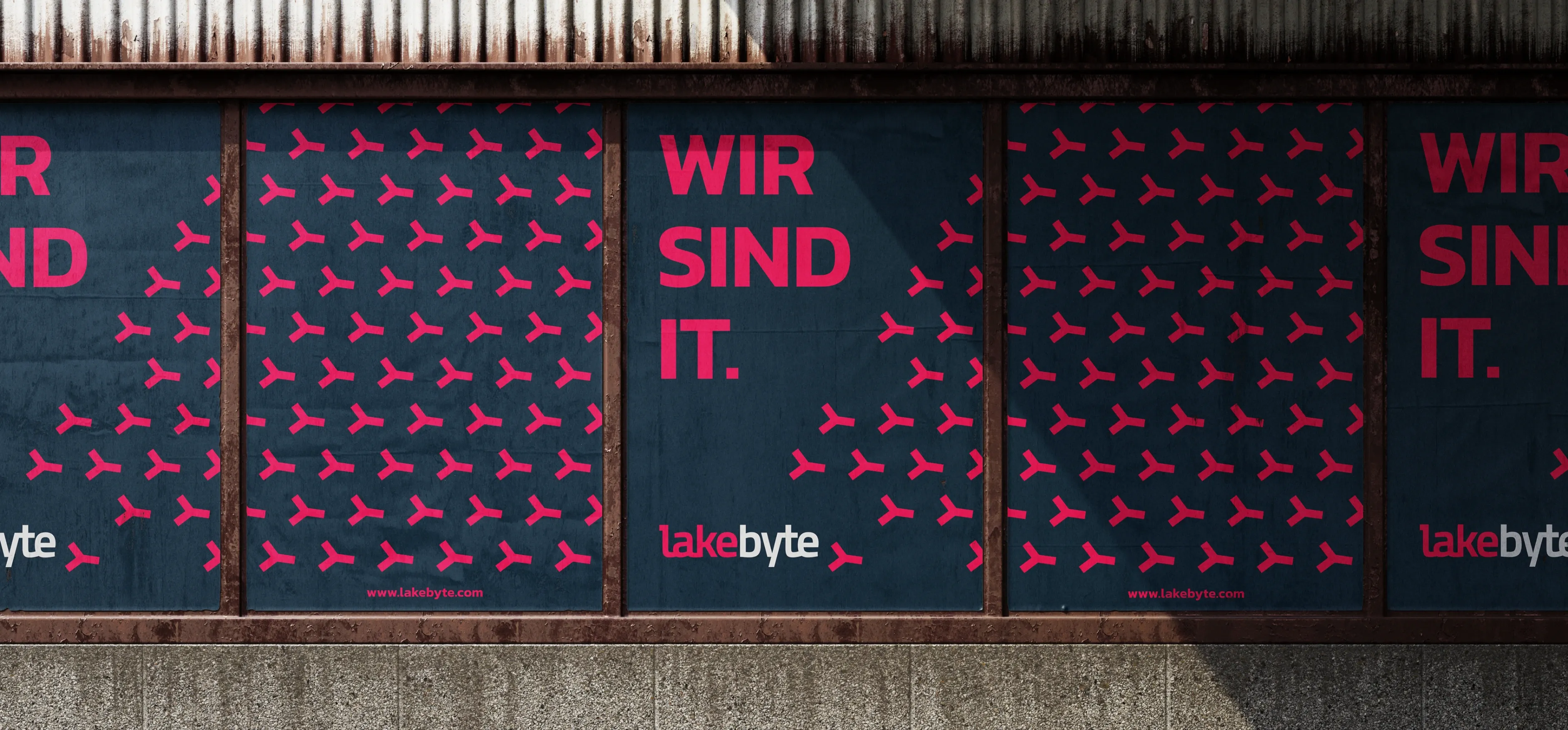 Mehrere lakebyte-Plakate an einer Fassade mit dem Claim ‚WIR SIND IT.‘ und wiederholtem Symbolmuster.